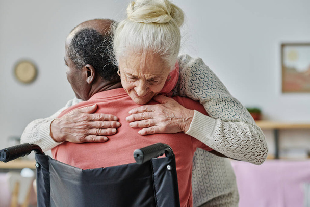 Mujer mayor abrazando al hombre con discapacidad durante la terapia de abrazo - Foto, Imagen