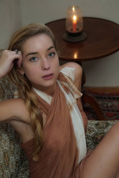 bela e sexy mulher loira sentada posando na sala de estar de sua casa em um vestido - Foto, Imagem