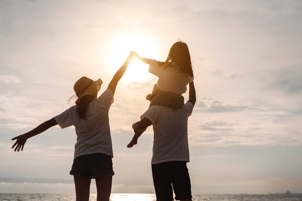 Boldog ázsiai család élvezni a tengerparton álló apa, anya és lánya szórakozás játszik strand a nyári vakáció az óceán partján. Boldog család nyaralás idő életmód koncepció. - Fotó, kép