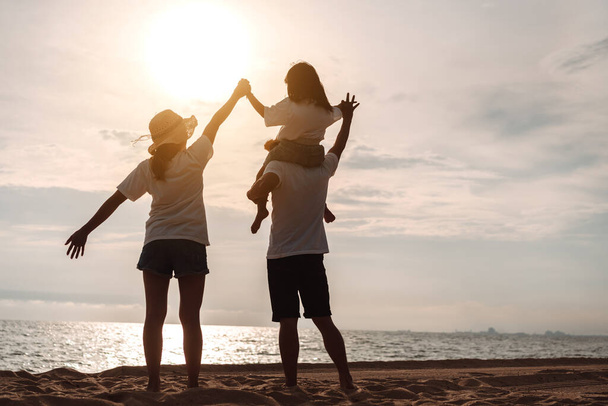 Happy asian family enjoy the sea beach at consisting father, mother and daughter having fun playing beach in summer vacation on the ocean beach. Happy family with vacations time lifestyle concept. - Fotó, kép