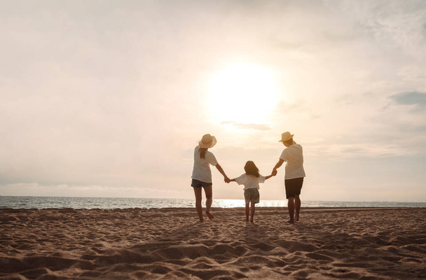 Happy asian family enjoy the sea beach at consisting father, mother and daughter having fun playing beach in summer vacation on the ocean beach. Happy family with vacations time lifestyle concept. - Foto, afbeelding