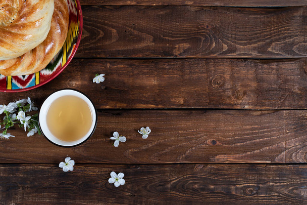 ταξίδι κέικ ψωμί στο πιάτο adras και teabowl με λευκά άνθη κεράσι σε ξύλινο φόντο. Ναβρούζ, κάρτα Ραμαζανιού. - Φωτογραφία, εικόνα