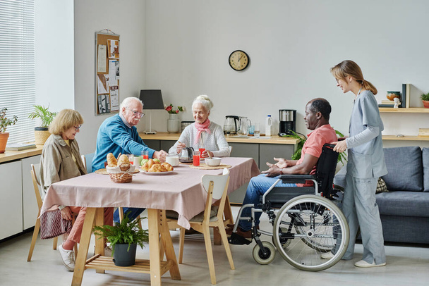Ryhmä vanhuksia istuu pöydässä ja syö aamiaista hoitokodissa - Valokuva, kuva