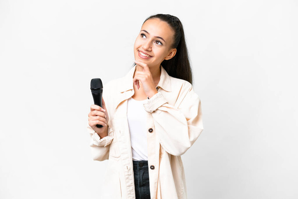 Fiatal énekes nő felvette a mikrofont elszigetelt fehér háttér és felnézett - Fotó, kép