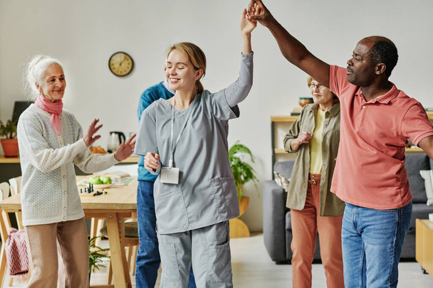 Vanhukset, joilla on tanssitunti hoitokodissa, tanssivat hoitajansa kanssa. - Valokuva, kuva