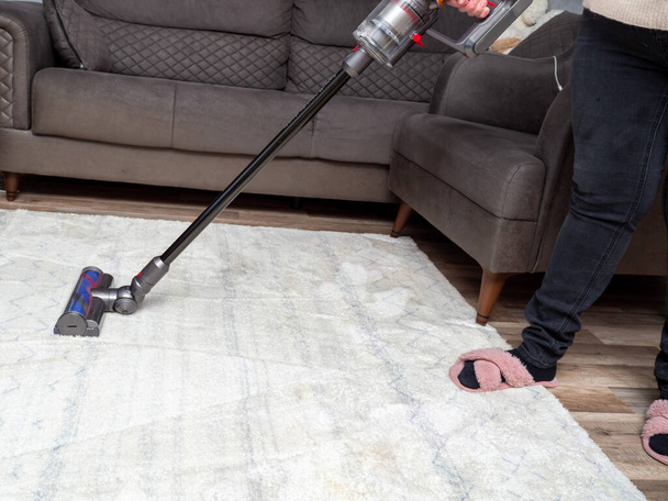 A woman vacuums the room with a modern vacuum cleaner. Cleaning of the apartment. Close-up. - Photo, Image