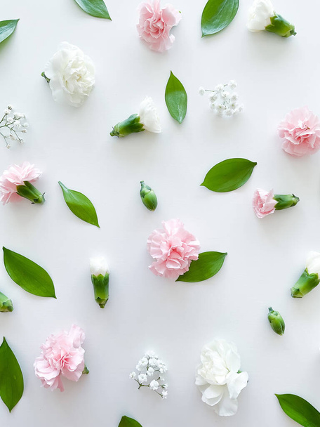 Florales Muster aus rosa und weißen Nelken, grünen Blättern, Knospen und Zigeunerblumen auf weißem Hintergrund. Flache Lage, Draufsicht. Valentins Hintergrund. Florales Muster. Blumenmuster. Mustertextur - Foto, Bild