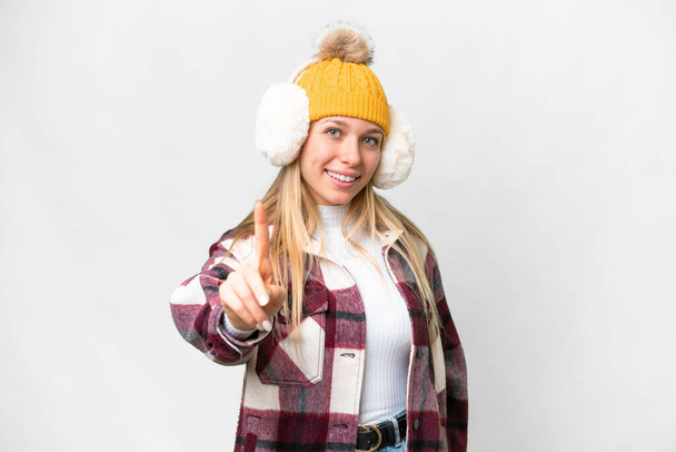 Молода красива блондинка в зимових муфтах над ізольованим білим тлом, що показує і піднімає палець
 - Фото, зображення