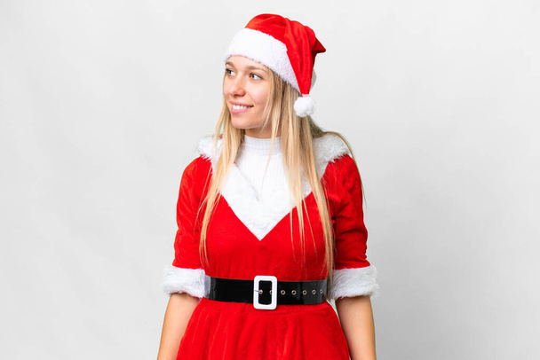 Jovem mulher loira com chapéu de Natal sobre fundo branco isolado olhando lado - Foto, Imagem