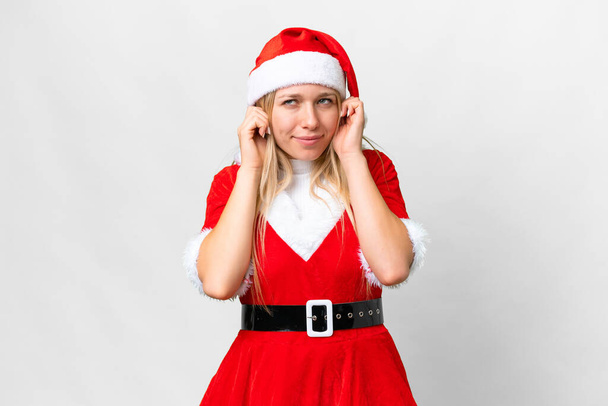 Jovem loira com chapéu de Natal sobre fundo branco isolado frustrado e cobrindo orelhas - Foto, Imagem