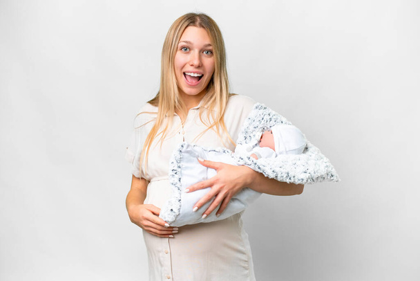 Young pretty pregnant woman with her newborn baby over isolated white background with surprise and shocked facial expression - Фото, зображення