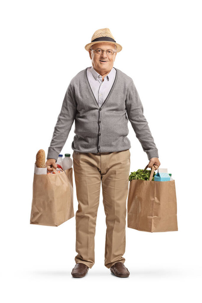 Full length portrait of an elderly man holding grocery bags isolated on white background - Photo, Image