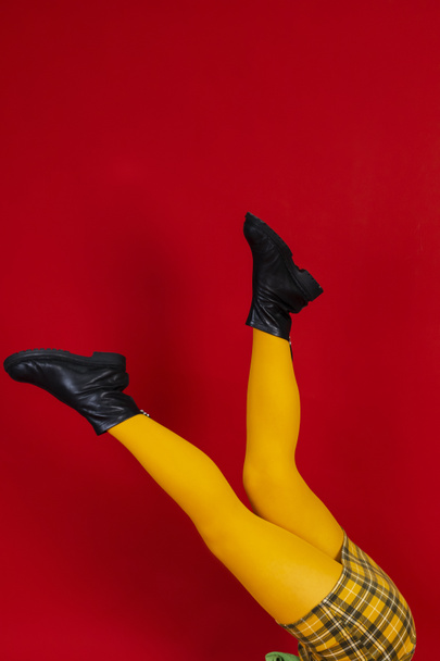 Gambe da donna in gonna gialla e leggins su fondo rosso isolato. copia spazio. - Foto, immagini