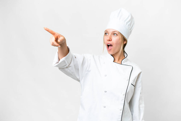 Молода шеф-кухарка над ізольованим білим тлом вказує геть
 - Фото, зображення