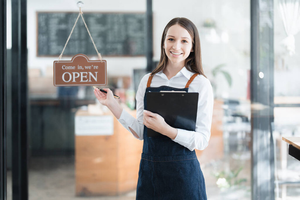 Starting and opening a small business, a young Asian woman showing a smiling face in an apron standing in front of a coffee shop bar counter. Business Owner, Restaurant, Barista, Cafe, Online SME. - Photo, Image