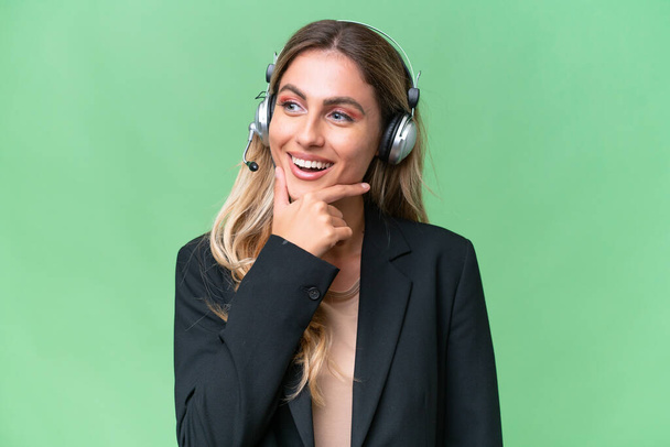Telemarketer pretty Uruguayan woman working with a headset over isolated background looking to the side - Foto, imagen