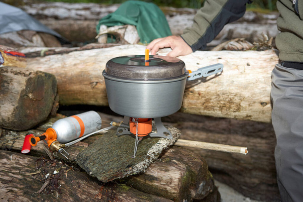 Man boiling water using camping gas stove - Фото, изображение