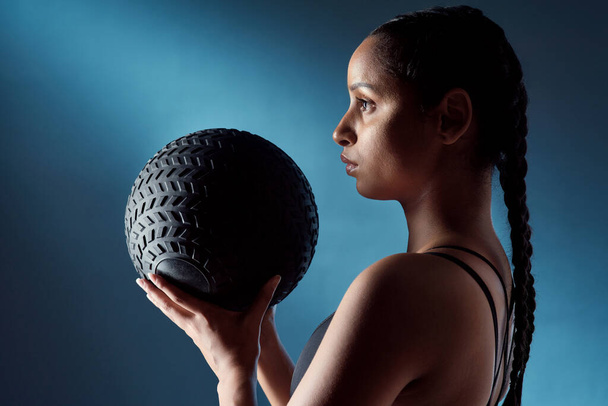 Fitness has become a necessary part of her life. Studio shot of a sporty young woman holding an exercise ball against a blue background - Zdjęcie, obraz