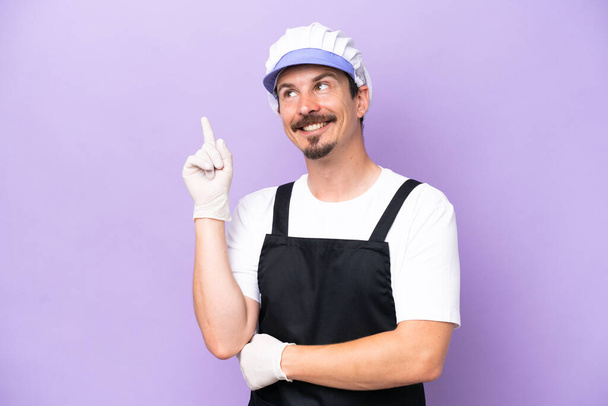Fishmonger man wearing an apron isolated on purple background pointing up a great idea - Photo, Image