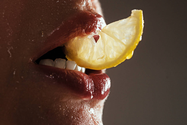 Sexy fruit. Closeup lips with lemons. Vitamin C. Summer refreshment concept. Tea time. Girl with slice of lemon. Macro closeup of mouth lips chewing yellow citrus - Fotó, kép