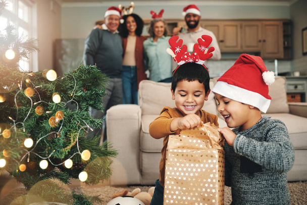 Noel, merak ve çocuklar hediyeleri açıyor, hediyelere ve kutulara birlikte bakıyorlar. Gülümse, şenlikli ve çocuklar bir hediye açmaya hazır ya da evde bayram kutlaması için ağacın altında hediye.. - Fotoğraf, Görsel