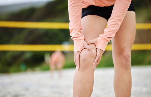 Sports knee pain, woman hands and beach volleyball injury of a athlete on sand with sport accident. Fitness, exercise and training bruise by sea and ocean with muscle strain from workout and running. - Fotó, kép