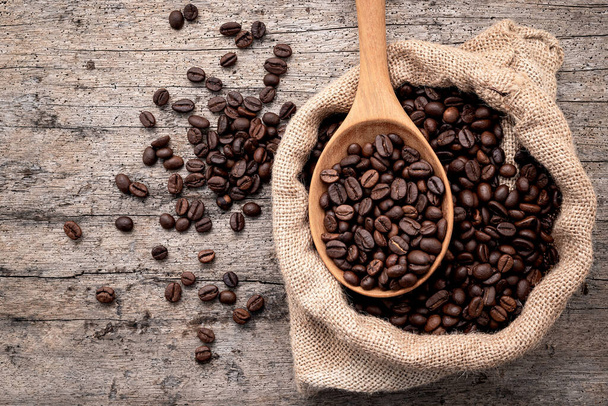 Background of dark roasted coffee beans with scoops setup on wooden background with copy space. - Valokuva, kuva
