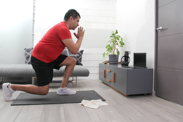 Aşırı kilolu Latin yetişkin bir adam sağlıklı olmak için evinde bilgisayarla egzersiz yapıyor. - Fotoğraf, Görsel