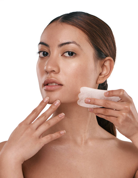 Gute Haut ist alles, was Sie in Ihrer Hautpflege-Routine tun. eine schöne Frau mit einem Gua Sha-Werkzeug im Gesicht - Foto, Bild