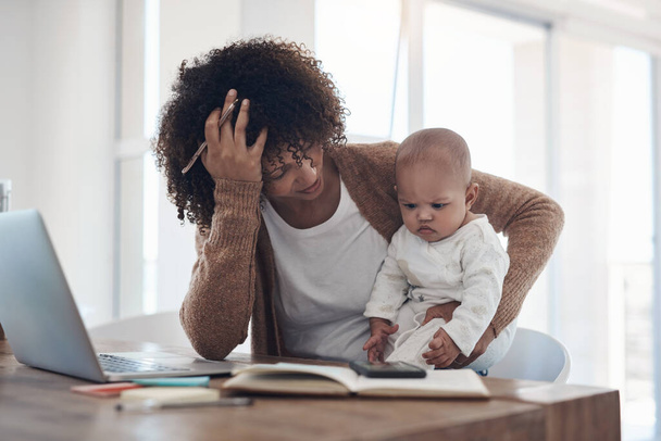 Splitting her attention gave her a splitting headache. a young woman looking stressed while caring for her adorable baby girl and working at home - Zdjęcie, obraz