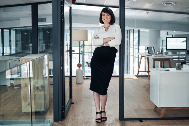 Welcome to the world of business. Full length shot of an attractive pregnant businesswoman standing alone in her office with her arms folded - Foto, Bild