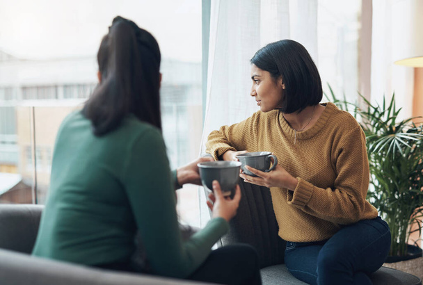 A tua paixoneta deve passar a qualquer momento. duas jovens mulheres bebendo café enquanto sentadas juntas em casa - Foto, Imagem