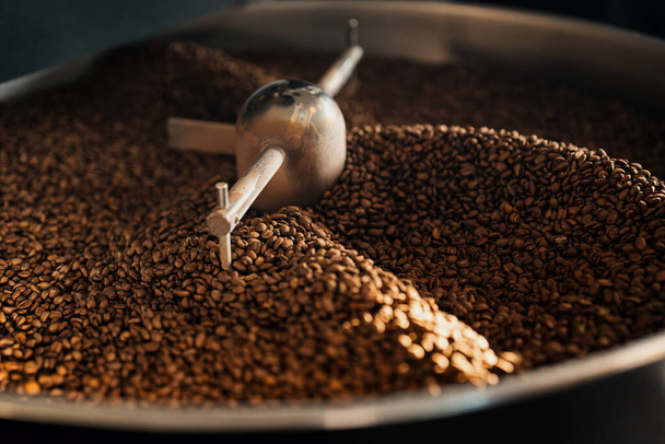 Υψηλή γωνία αρωματικών φρεσκοψημένων κόκκων καφέ σε μεγάλο δίσκο ψύξης της μηχανής ψησίματος στο εργοστάσιο - Φωτογραφία, εικόνα