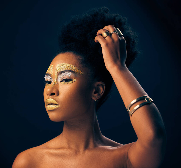 Ομορφιά, χρυσό και glitter με μαύρη γυναίκα και μακιγιάζ στο studio για πολυτέλεια, καλλυντικά ή Αφρικανική υπερηφάνεια. Φυσική, δημιουργική και θεά με γυναικείο μοντέλο σε μαύρο φόντο για ντάμα, μπρούντζο ή αίγλη. - Φωτογραφία, εικόνα