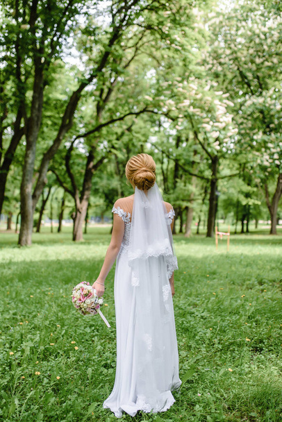 молода красива весільна наречена гуляє на природі в парку в красивій сукні. Високоякісна фотографія
 - Фото, зображення