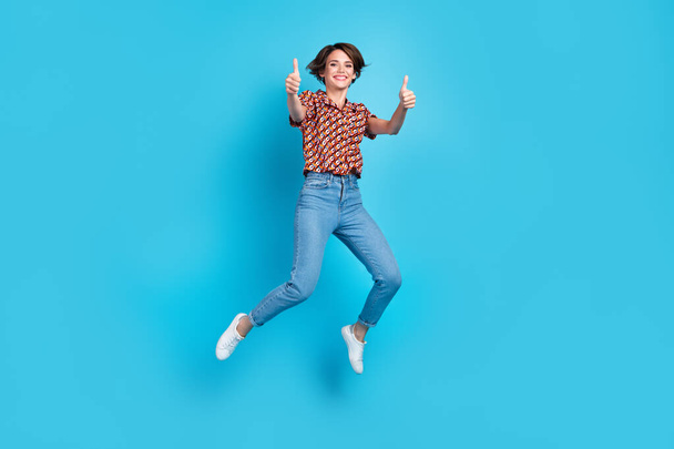 Full body portrait of carefree cheerful lady jumping demonstrate thumb up isolated on blue color background. - Φωτογραφία, εικόνα