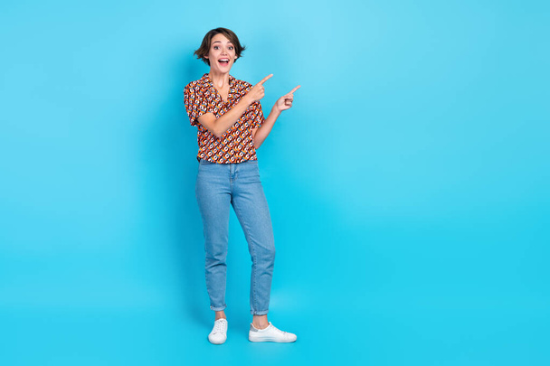 Full length portrait of astonished cheerful person indicate fingers empty space isolated on blue color background. - Fotografie, Obrázek