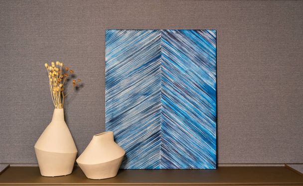 Abstrakcyjny wzór w postaci pasków zbiegających się linii obok figurek glinianych wazonów w minimalistycznym wnętrzu. - Zdjęcie, obraz