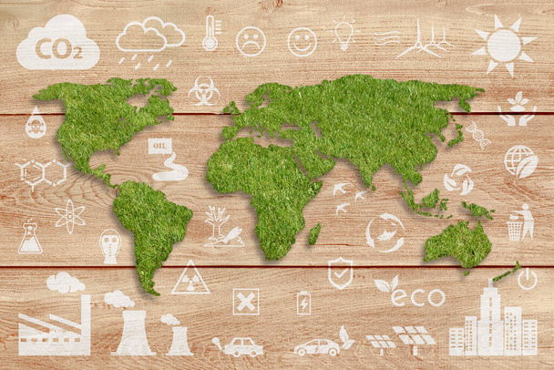 Ecologisch concept: duurzame wereld. Een groen gras textuur Wereld kaart boven een bruin hout planken paneel, met verschillende witte ecologie pictogrammen op de achtergrond. - Foto, afbeelding