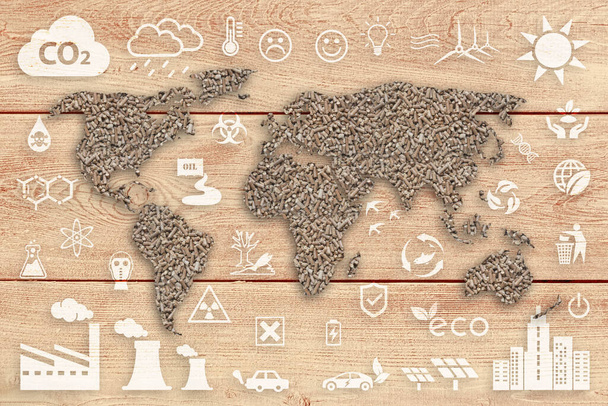 Concepto ecológico: mundo sostenible. Un mapa mundial texturizado de pellets de madera sobre un panel de tablones de madera marrón, con varios iconos de la ecología blanca superpuestos sobre el fondo. - Foto, imagen