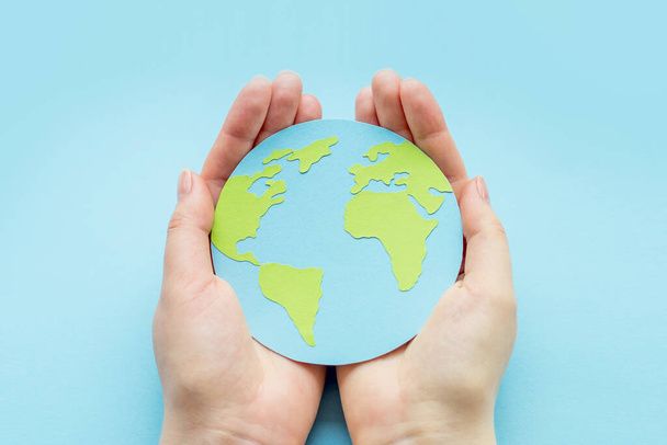 Maailman ympäristöpäivän käsite. Kaksi ihmiskättä, jotka pitelevät maapalloa sinisellä pohjalla. Maan päivä - Valokuva, kuva