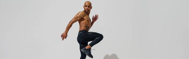 Active sporty man with naked torso jumping on white studio background. Dynamic movement - 写真・画像