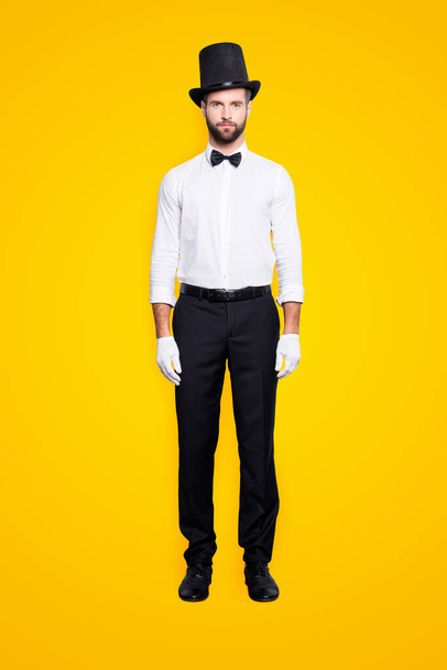 Full size fullbody portrait of stylish attractive magician in tophat, formal wear, bow, looking at camera, isolated on grey background. - Foto, imagen