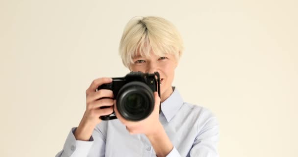 Mujer fotógrafa tomando fotos en cámara profesional sobre fondo blanco retrato 4k película cámara lenta. Concepto de fotografía Hobby - Metraje, vídeo