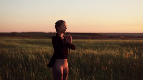  Young pretty girl woman meditating with closed eyes, praying while standing in a field with a beautiful view on a windy autumn day at sunset - Footage, Video