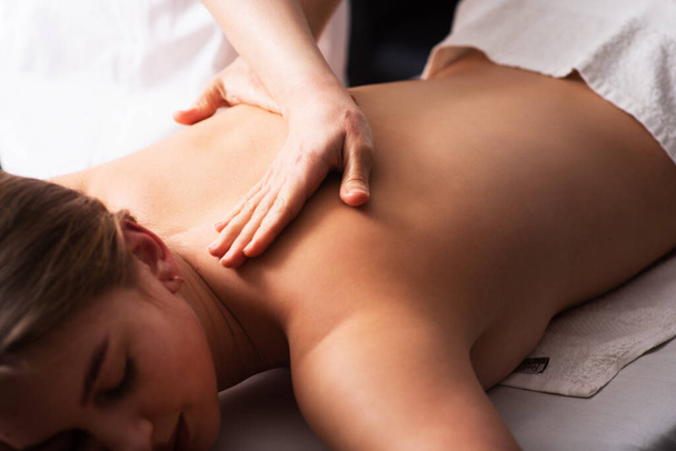 masażysta masujący plecy i łopatki młodej kobiety na stole do masażu na białym tle. Koncepcja zabiegów spa masażu. procedury relaksacyjne organizmu. Zbliżenie - Zdjęcie, obraz