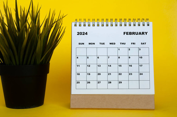 Febrero 2024 calendario de meses con planta de mesa sobre fondo de cubierta amarilla. Concepto de calendario mensual - Foto, imagen