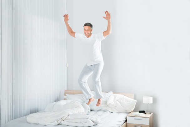 男はベッドの上をジャンプ - 写真・画像