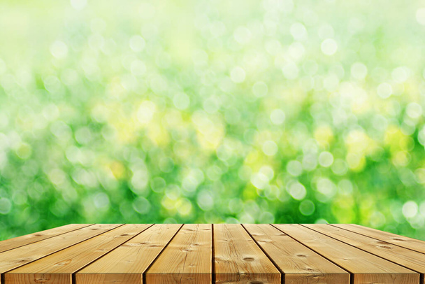 Ecology background: a brown empty wood planks table on green natural bokeh background. - Photo, Image