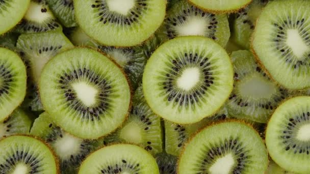 Zielone plastry owoców Kiwi powoli obracające się na czarnym tle. Świeże i soczyste przekąski pakowane witaminami - Materiał filmowy, wideo